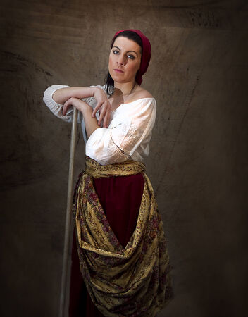 Phesant girl posing with tool wearing old world attire and scarf on headの写真素材