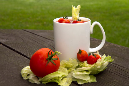 Tomato soup cocktail concept with small cherry tomatoes in drink with lettuceの写真素材