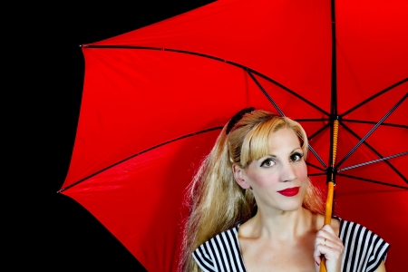 Young woman and her large red umbrella isolated on black backgroundの写真素材