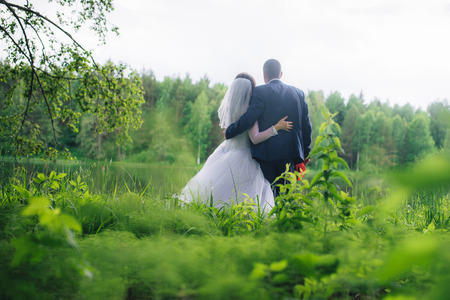 bride and groom standing in front of the lake and looking into the distance.