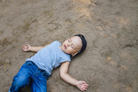 Little boy laying on ground pretending sleep or unconscious.の写真素材
