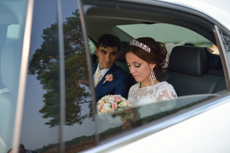 Happy romantic newlyweds, bride and groom sitting in wedding car.の写真素材