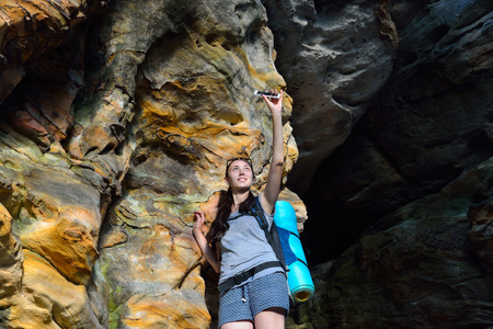 Woman Hiker with backpack making photo on smartphone with coloresd stone wall as background.の写真素材