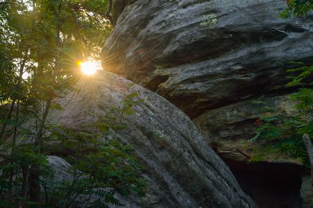 Sun looks out between big rocks, morning in mountains.の写真素材