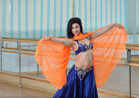 Beautifull caucasian woman in costume for belly-dance is dancing indoors at dance class.の写真素材