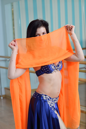 Beautifull caucasian woman in costume for belly-dance is dancing indoors at dance class.の写真素材