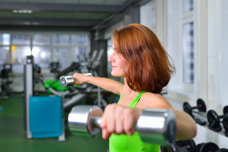 fitness, sport, training and lifestyle concept - woman in gym exercises weight lifting.の写真素材