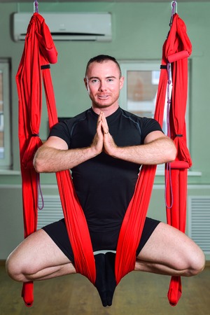 Anti-gravity Yoga, man doing aero-yoga exercises with hammock in class.の写真素材