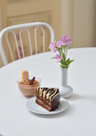 Delicious chocolate cake and dessert near with flowers on white table in cafe.の写真素材