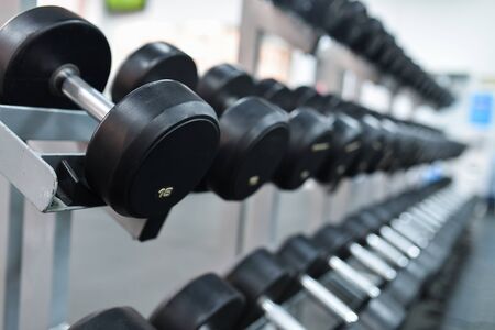 Row of heavy iron dumbbells on a rack at gym.の写真素材