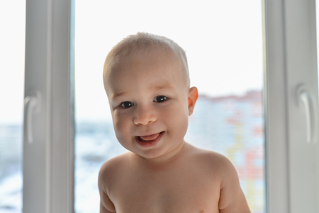 Portrait of a happy little boy standing near windowの写真素材