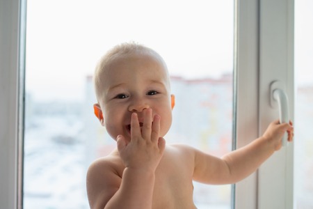 Portrait of a happy little boy standing near windowの写真素材