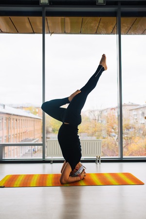 Experienced yoga man doing various  pose and stretching exercises indoors, panoramic city view at backgroundの写真素材