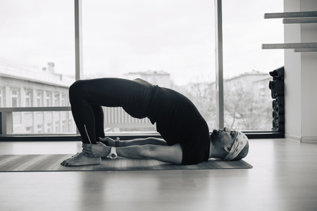 Experienced yoga man doing various  pose and stretching exercises indoors, panoramic city view at backgroundの写真素材