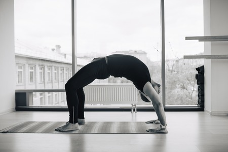 Experienced yoga man doing various  pose and stretching exercises indoors, panoramic city view at backgroundの写真素材