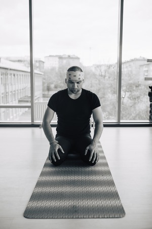 Experienced yoga man doing various poses indoors, panoramic city view at backgroundの写真素材