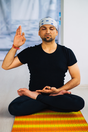 Indian man doing yoga practice indoors, full lotus meditation postureの写真素材