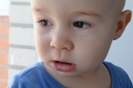 Serious child attentive looks out of the windowの写真素材