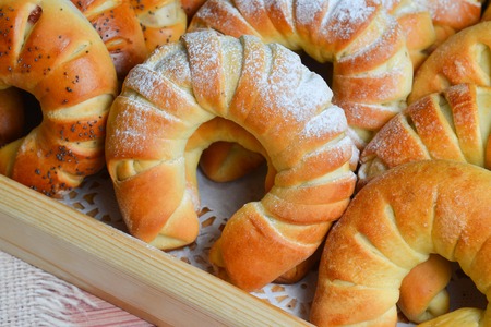 Fresh just baked sweet buns or bread rolls on tray for breakfast and tea or coffee time on wooden backgroundの写真素材