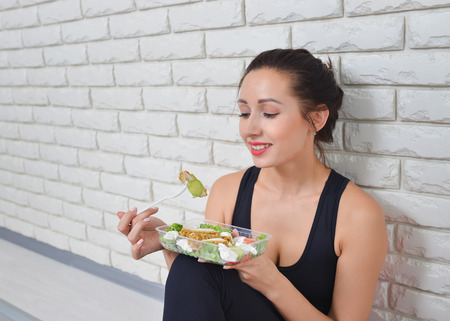 Fit healthy woman in sportswear eating a fresh salad after fitness workout.の写真素材