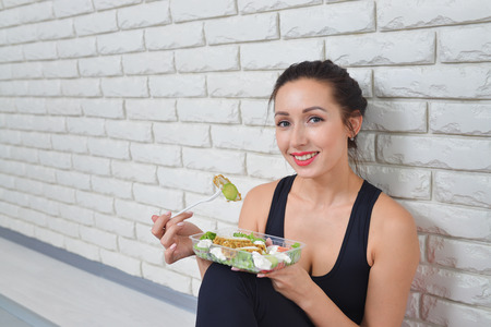 Fit healthy woman in sportswear eating a fresh salad after fitness workout.の写真素材