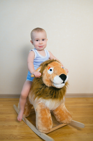 Cute small baby boy riding on the lion toy . Happy child emotions.の写真素材