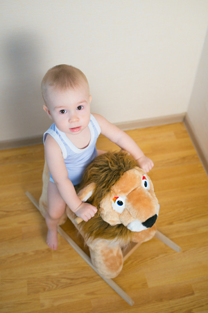 Cute small baby boy riding on the lion toy . Happy child emotions.の写真素材