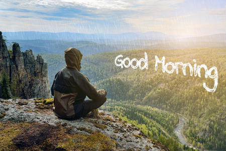 Man hiker sitting on top of mountain meeting sunrise, Good Morning lettering in form of clouds.の写真素材