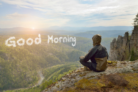 Man hiker sitting on top of mountain meeting sunrise, Good Morning lettering in form of clouds.の写真素材