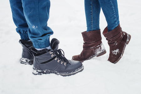 Closeup of male and female legs during a date in winter, shorter woman slid up to reach taller man on love scene, couple kissing.の写真素材