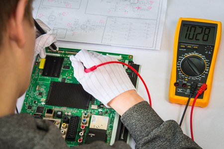 Computer repair service, hands of man tech testing motherboard with toolsの写真素材