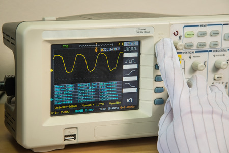 Modern oscilloscope, mans hand adjusting wave signals, closeupの写真素材