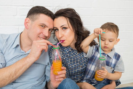 Family having fun drinking orange juice using strawsの写真素材