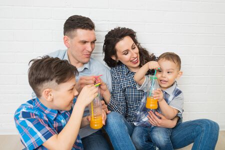 Family having fun drinking orange juice using strawsの写真素材