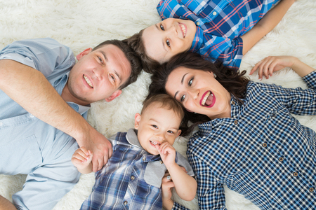 Happy family, mother, father and two sons having fun lying on the floor, upper viewの写真素材