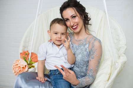 Happy family of young beautiful mother in plum dress and little positivity son, gesturing victory by fingers.の写真素材