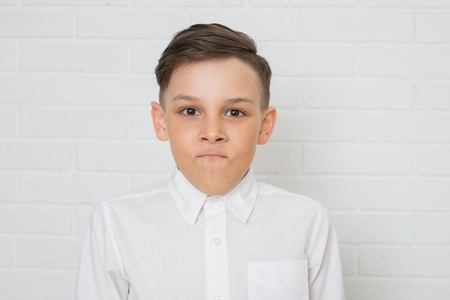 Portrait of angry boy in white shirt . Negative human emotion, facial expression. Closeupの写真素材