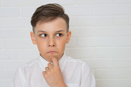 Young boy thinkin on white background looking at the sideの写真素材