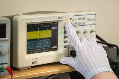 Modern oscilloscope, mans hand adjusting wave signals, closeupの写真素材