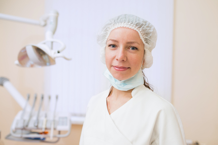 Portrait of young female dentist, standing in dental office smiling and looking at camera.の写真素材