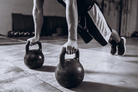 Handsome Strong man workout at gym, strength pushup exercise with Kettlebell.の写真素材