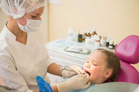 Little cute girl sitting in chair at dentist clinic during dental checkup and treatment.の写真素材