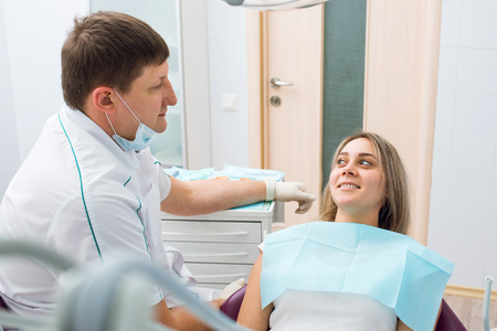 Male dentist and woman at dentaloffice. Patient and doctor during conversationの写真素材