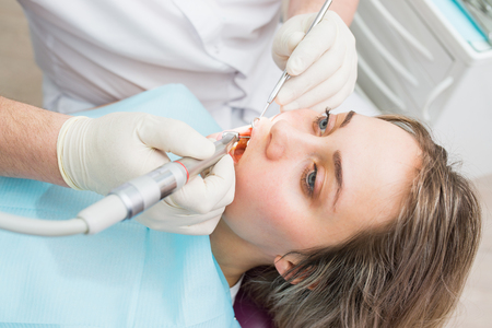 Dentist curing a female patient with drill, closeup.の写真素材