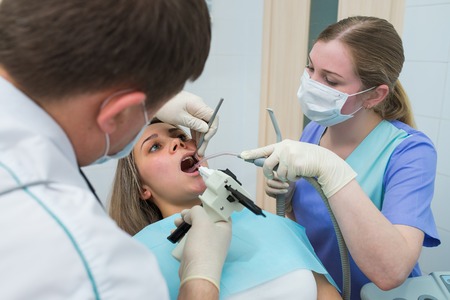 dentist treating patients teeth with special instrumentsの写真素材