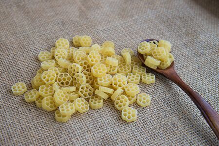 Raw pasta in wooden spoon on sack rustic background . Natural and healthy food concept.の写真素材