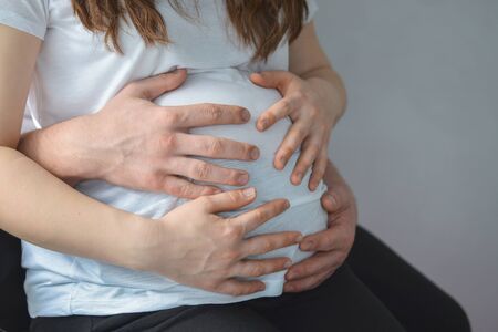 Man holding pregnant woman belly carefully closeup detail shootの写真素材