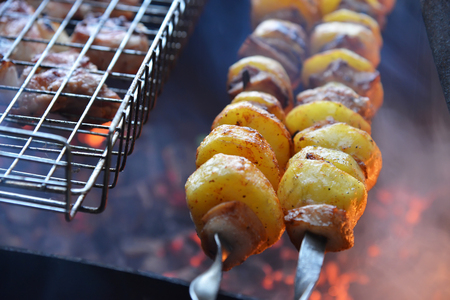 Grilled potato on the skewers with lard pieces on fireの写真素材