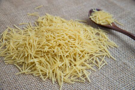 Filini raw pasta in wooden spoon on sack rustic background . Natural and healthy food conceptの写真素材