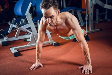 Handsome caucasian man working out and doing push ups at gym. Bodybuilding, sport and fitness lifestyle.の写真素材